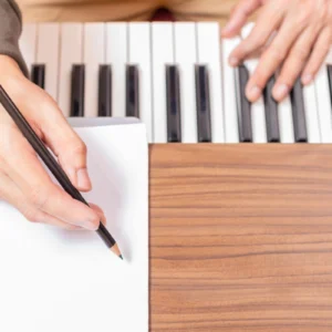 Hands writing and playing piano keyboard.