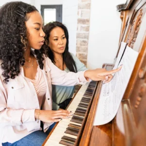 Girl and woman practicing piano together.