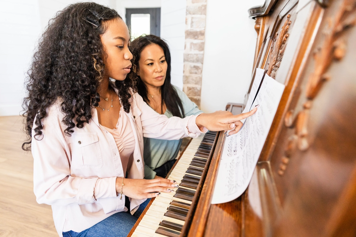 Girl and woman practicing piano together.