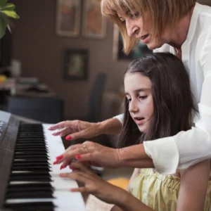 Woman teaching girl to play keyboard.