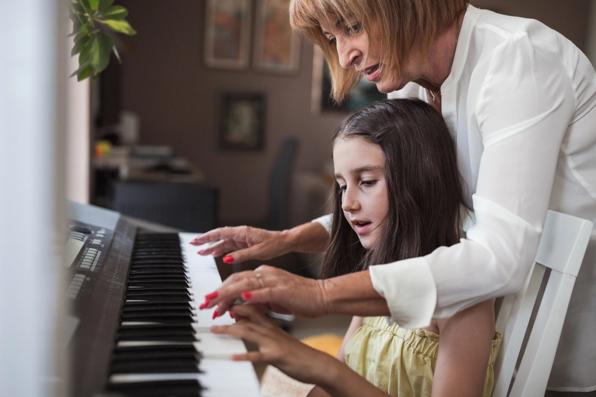 Woman teaching girl to play keyboard.