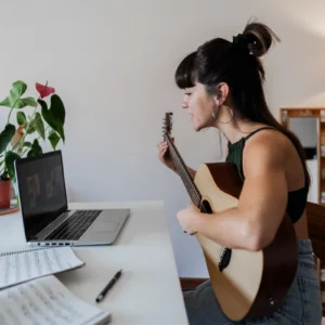 Woman playing guitar during online lesson.