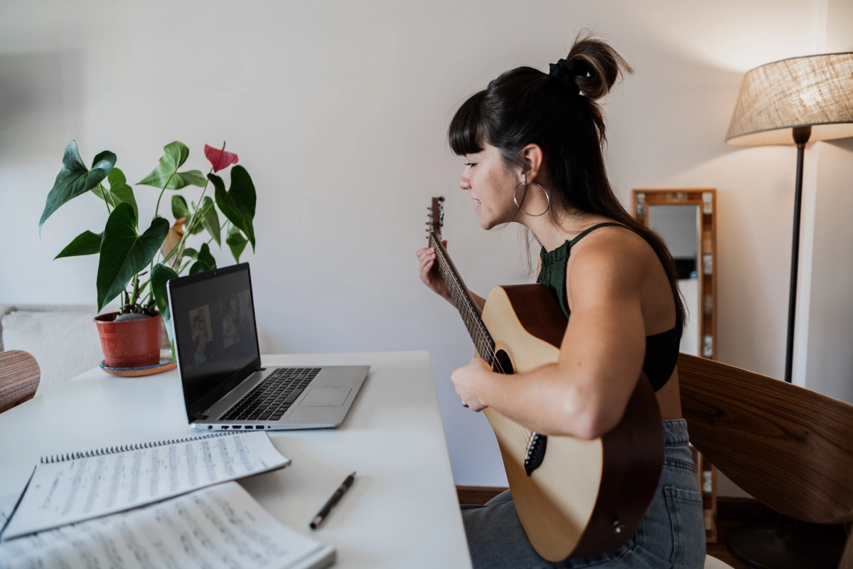 Woman playing guitar during online lesson.