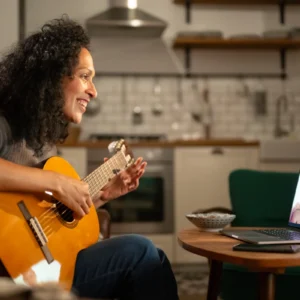 Woman playing guitar during a video call.