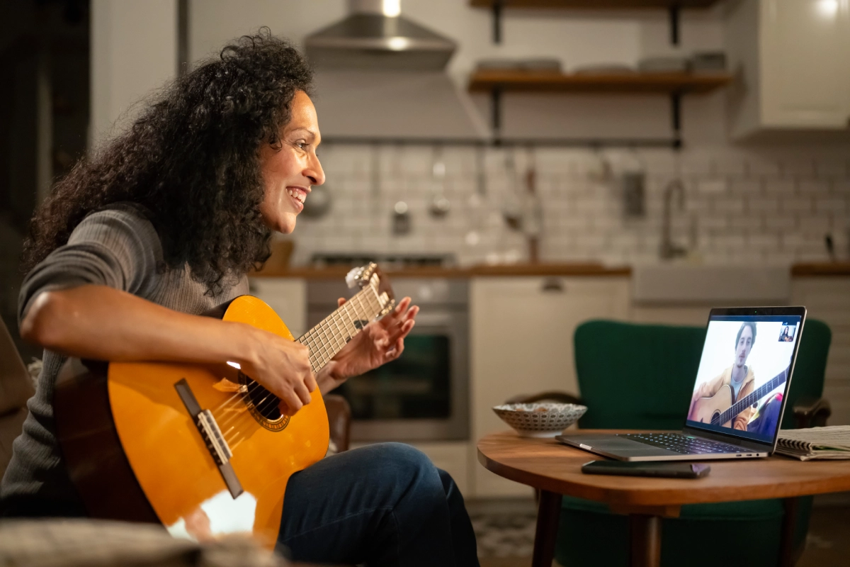 Woman playing guitar during a video call.
