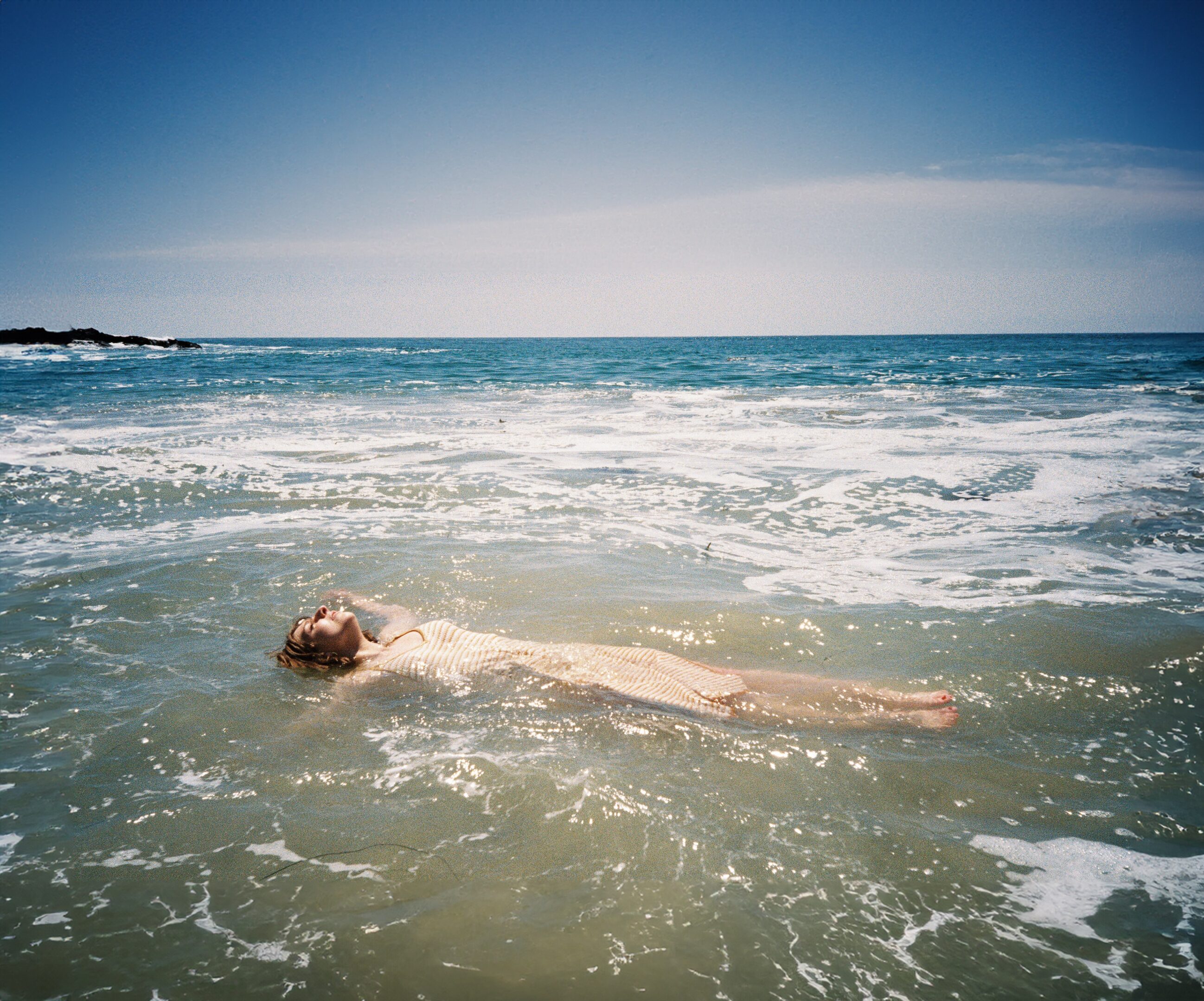Person floating peacefully in ocean water.